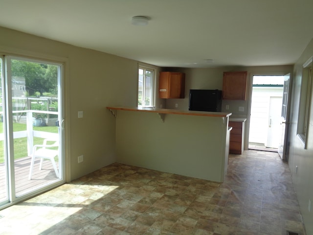 kitchen with a kitchen bar, kitchen peninsula, and black refrigerator