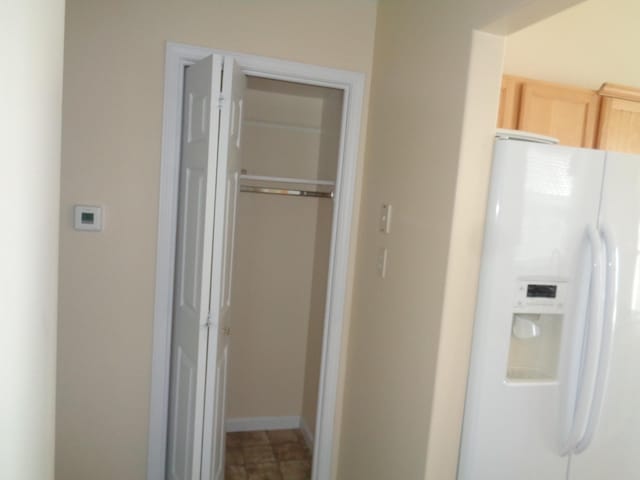 interior space featuring light brown cabinets and white refrigerator with ice dispenser