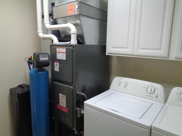 clothes washing area with cabinets and washing machine and clothes dryer