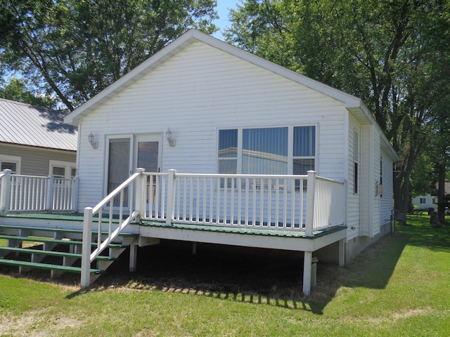 rear view of property featuring a lawn and a deck