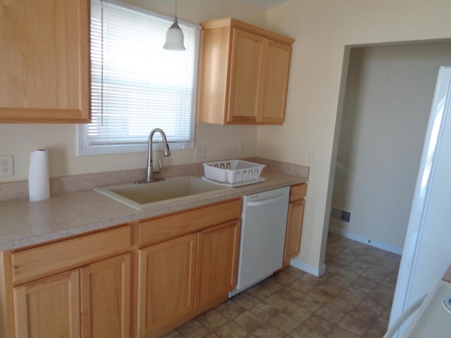 kitchen featuring light brown cabinetry, dishwasher, hanging light fixtures, and sink