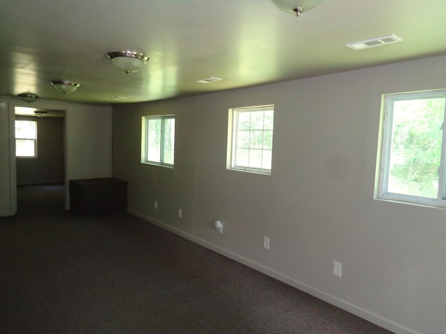 empty room featuring plenty of natural light and dark carpet