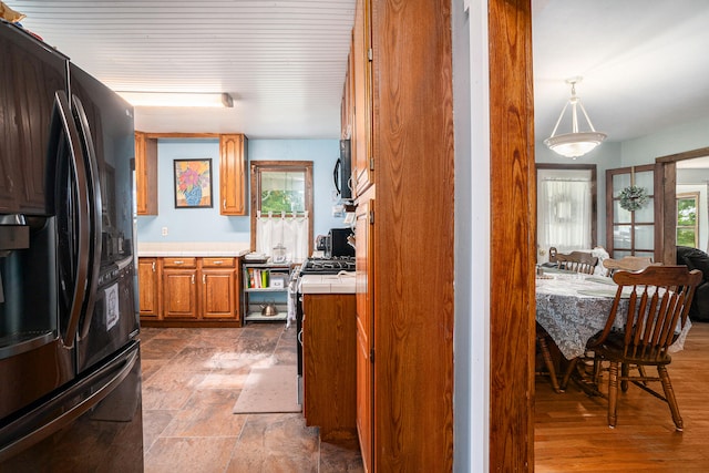 kitchen with plenty of natural light, dark wood-type flooring, pendant lighting, and black fridge