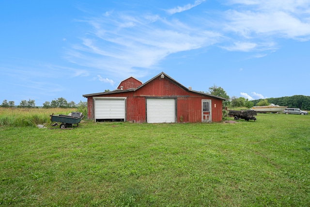 view of side of home with a garage, a yard, and an outbuilding