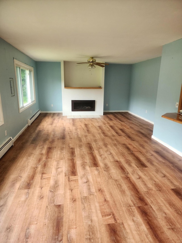 unfurnished living room featuring light wood-type flooring, baseboard heating, and ceiling fan