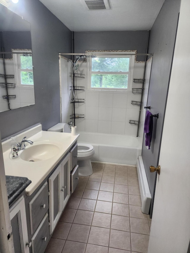 full bathroom featuring baseboard heating, tile patterned floors, toilet, vanity, and tiled shower / bath