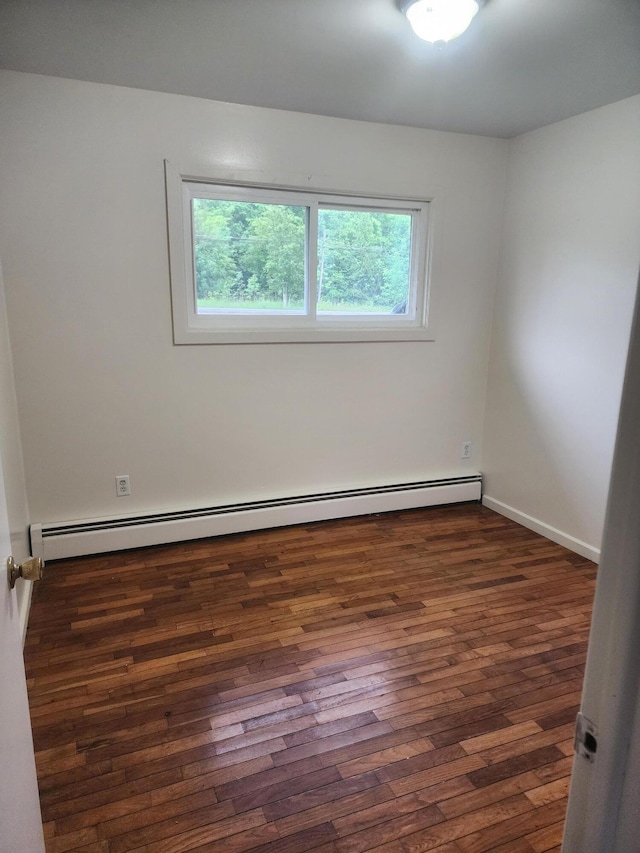 empty room with dark hardwood / wood-style flooring and a baseboard heating unit