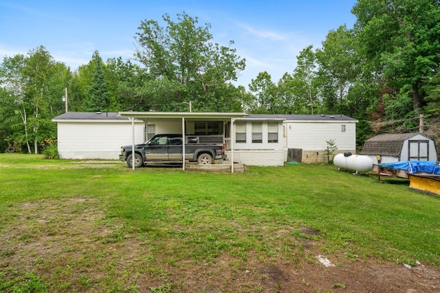 back of property with a carport, a shed, and a lawn