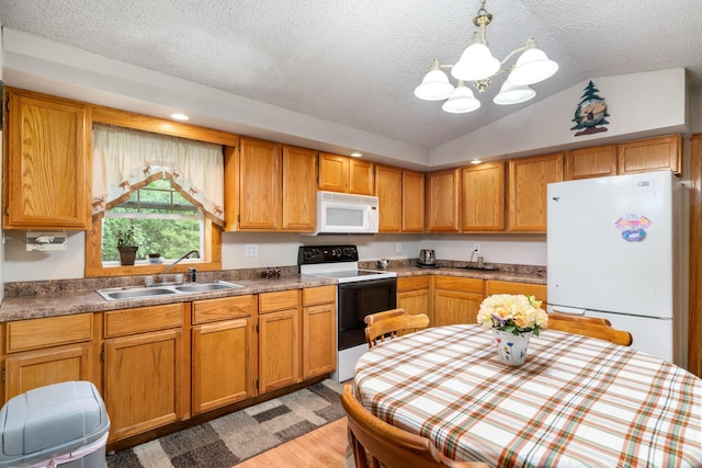 kitchen featuring lofted ceiling, sink, hanging light fixtures, light wood-type flooring, and white appliances