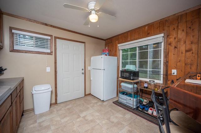 kitchen featuring white refrigerator, wood walls, ceiling fan, and crown molding