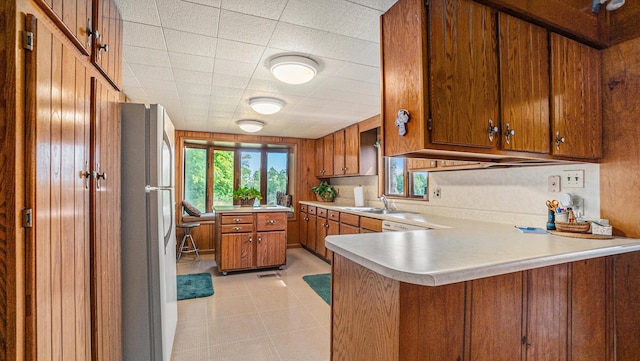 kitchen with refrigerator, kitchen peninsula, and sink