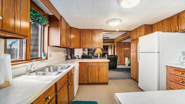 kitchen with light tile patterned flooring, sink, wood walls, kitchen peninsula, and white appliances