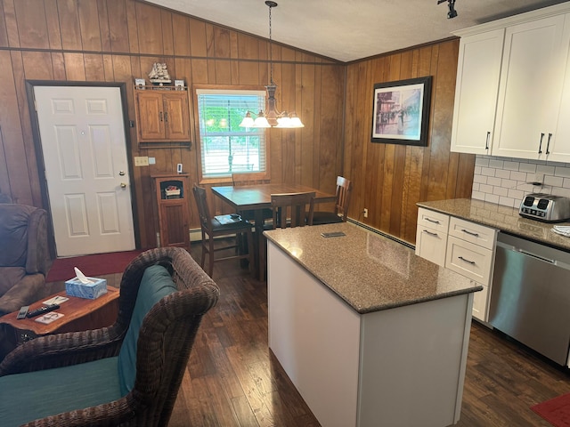 kitchen featuring a kitchen island, white cabinetry, dishwasher, wooden walls, and decorative light fixtures