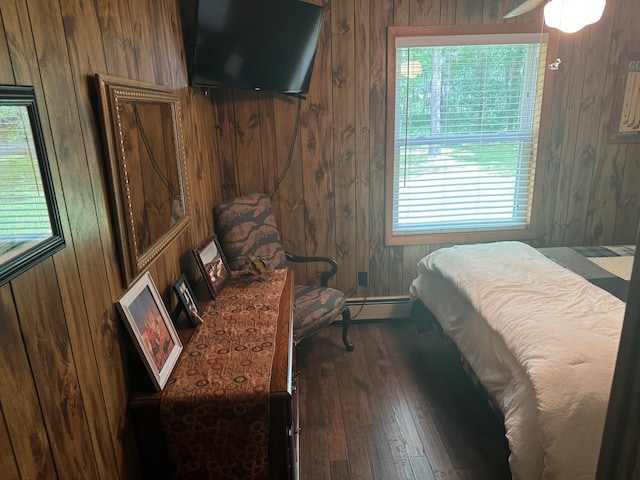 bedroom with multiple windows, dark hardwood / wood-style flooring, and wooden walls