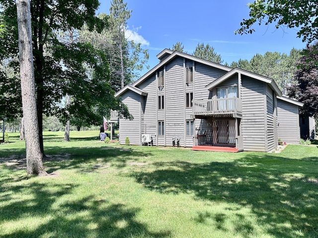 back of house with a balcony and a yard