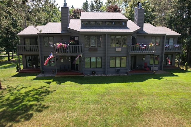 rear view of property featuring a balcony, a patio area, and a lawn