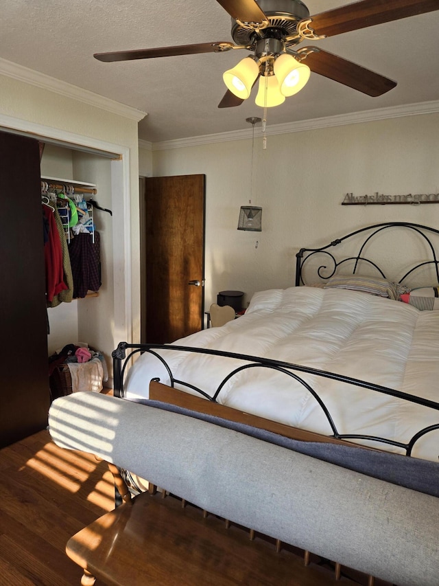 bedroom featuring ceiling fan, ornamental molding, dark hardwood / wood-style flooring, and a closet