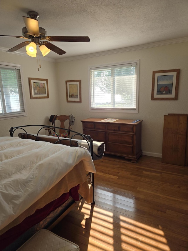 bedroom featuring ceiling fan, dark wood-type flooring, ornamental molding, and a textured ceiling