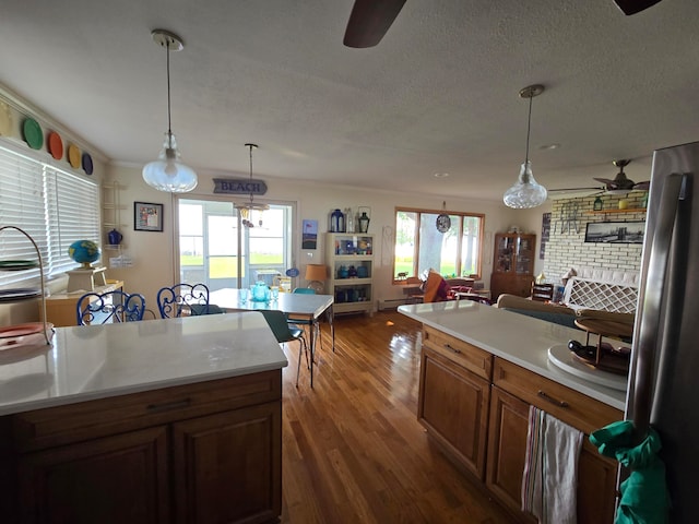 kitchen with dark hardwood / wood-style floors, stainless steel refrigerator, decorative light fixtures, ceiling fan, and a textured ceiling