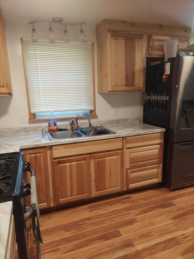 kitchen with stainless steel fridge with ice dispenser, light wood-type flooring, sink, and range