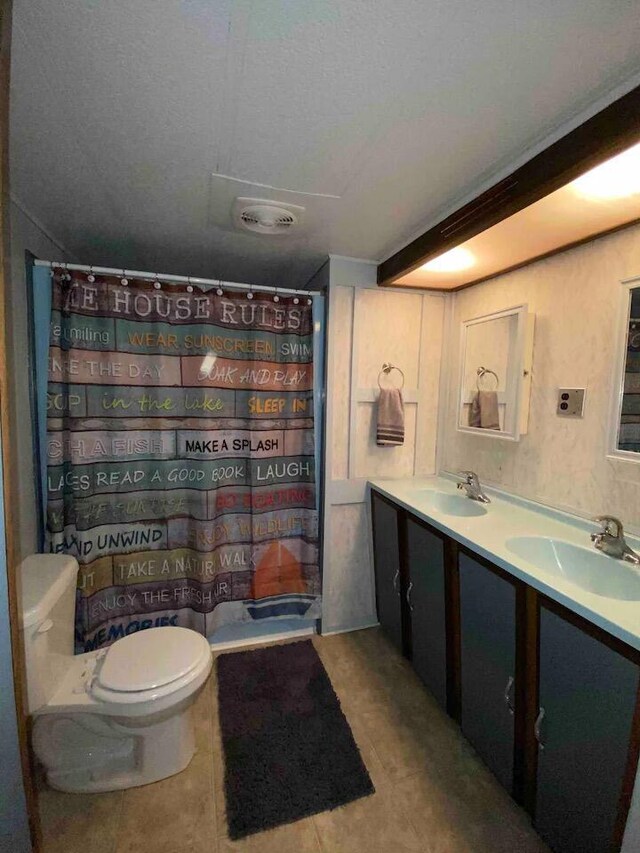 bathroom with dual vanity, toilet, and tile patterned floors