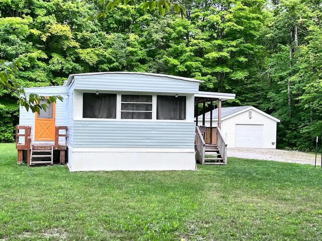 manufactured / mobile home with a garage, an outdoor structure, and a front yard