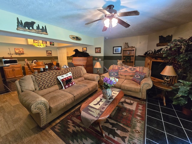 living room with ceiling fan, hardwood / wood-style flooring, and a textured ceiling