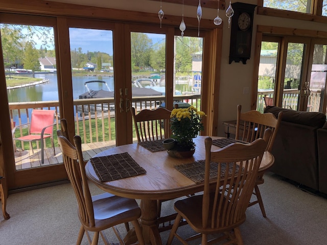 carpeted dining area featuring plenty of natural light, french doors, and a water view