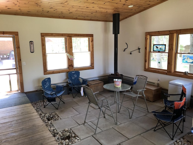 dining area featuring lofted ceiling, wood ceiling, and a wood stove