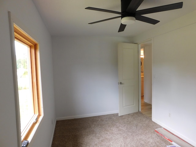 carpeted empty room featuring a wealth of natural light and ceiling fan