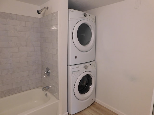 washroom with light hardwood / wood-style floors and stacked washer and dryer