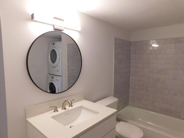 full bathroom featuring vanity, stacked washer and clothes dryer, toilet, and tiled shower / bath