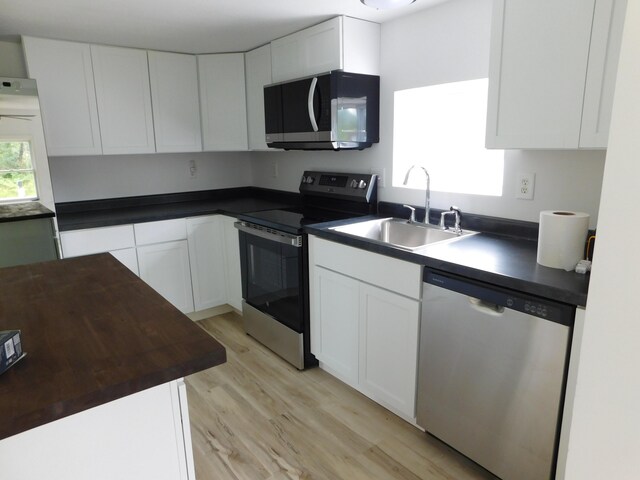 kitchen with sink, white cabinets, light wood-type flooring, and stainless steel appliances