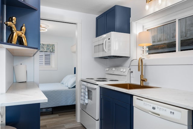 kitchen with white appliances, sink, light stone countertops, blue cabinetry, and wood-type flooring