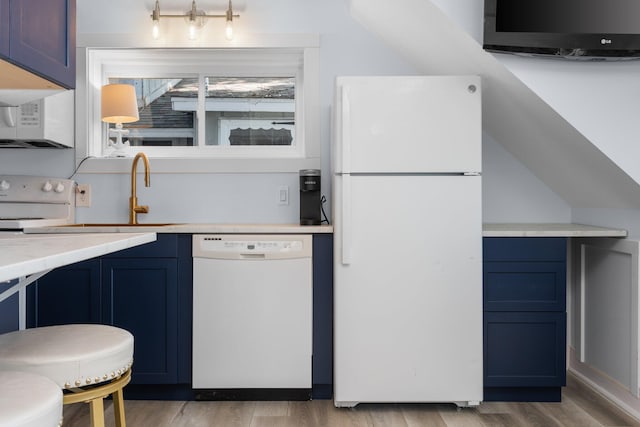 kitchen with blue cabinetry, white appliances, and light hardwood / wood-style flooring