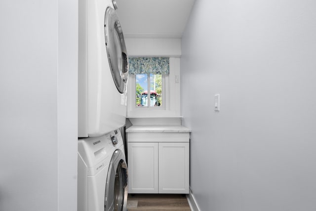 laundry area featuring dark hardwood / wood-style flooring, cabinets, and stacked washer / drying machine