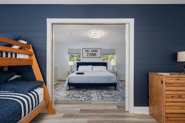 bedroom with wood walls and light hardwood / wood-style flooring