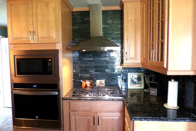 kitchen featuring wall chimney exhaust hood, dark stone countertops, decorative backsplash, and appliances with stainless steel finishes