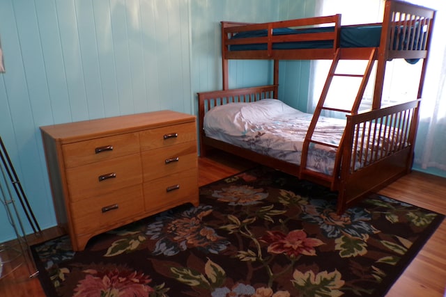 bedroom with wood walls and hardwood / wood-style flooring