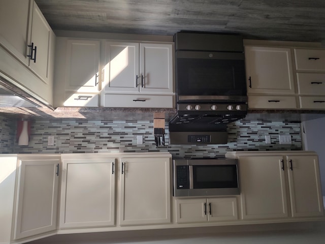 kitchen featuring stainless steel microwave, white cabinetry, and tasteful backsplash