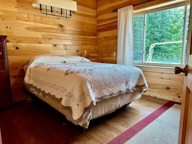 bedroom with wood walls and hardwood / wood-style flooring