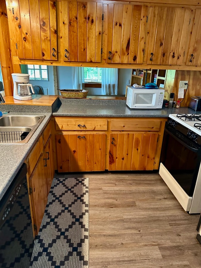 kitchen with kitchen peninsula, light hardwood / wood-style flooring, white appliances, and a wealth of natural light