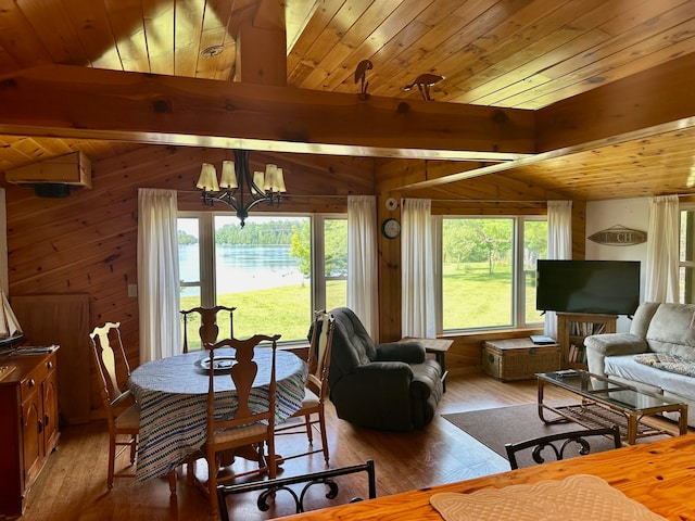 living room with light wood-type flooring, a wealth of natural light, wooden walls, and a chandelier