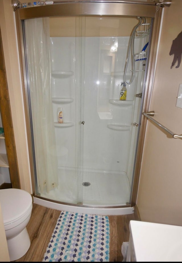 bathroom featuring walk in shower, toilet, and hardwood / wood-style floors