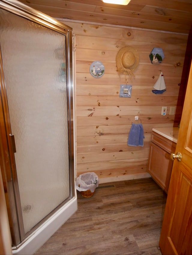 bathroom featuring wooden walls, vanity, walk in shower, and hardwood / wood-style floors