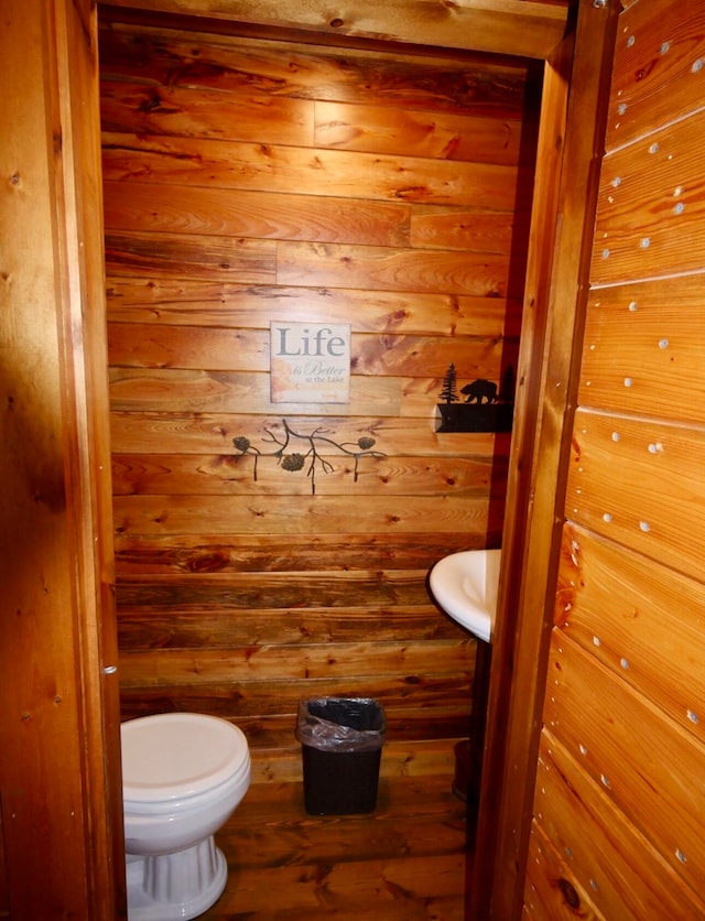 bathroom featuring wood walls, toilet, and hardwood / wood-style flooring