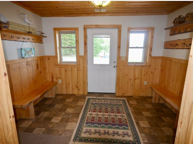 mudroom with wood ceiling, wooden walls, and dark tile patterned flooring