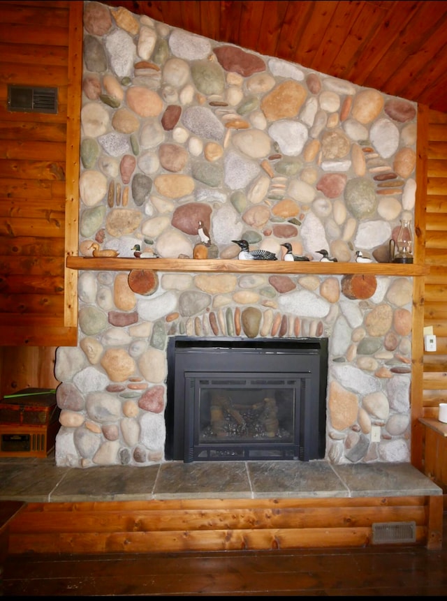 room details featuring a stone fireplace, wooden walls, and rustic walls