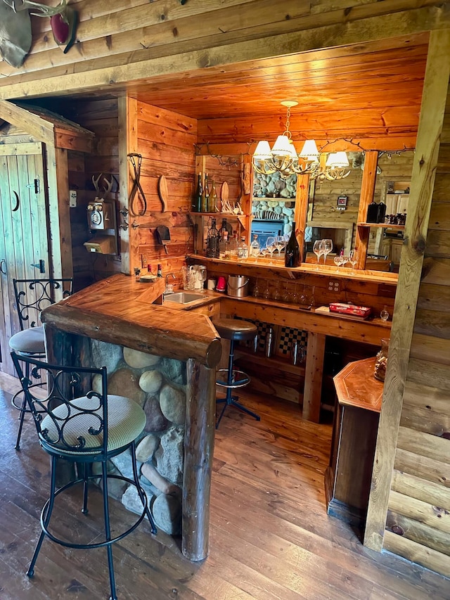 bar with wood-type flooring, pendant lighting, log walls, wood walls, and wood ceiling