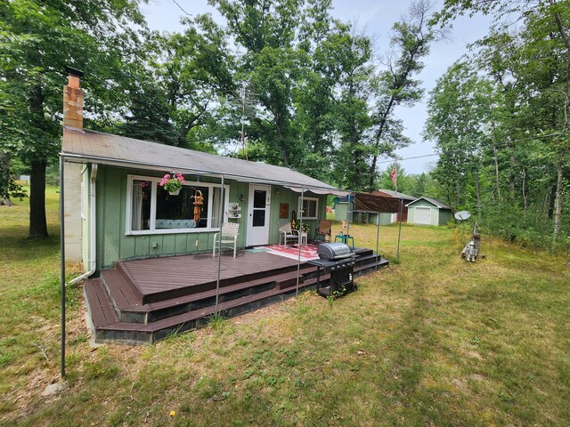 rear view of property featuring a wooden deck, a yard, and an outdoor structure